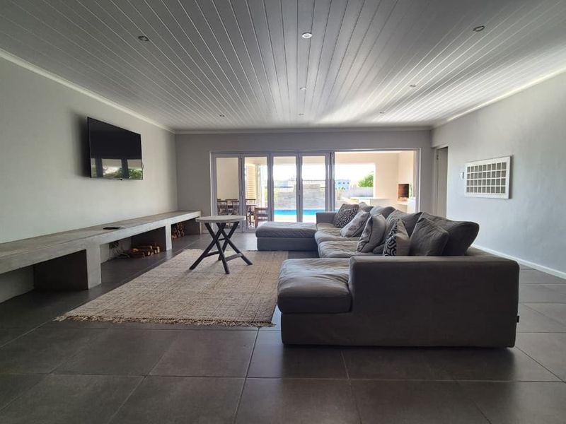 Spacious living room featuring tiled floors, a built-in concrete media console, and bi-fold doors opening to an outdoor pool area.