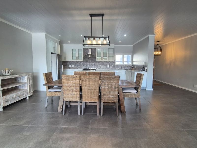 Spacious open-plan kitchen and dining area featuring modern cabinetry, tiled flooring, and stylish pendant lighting, creating a bright and functional living space.