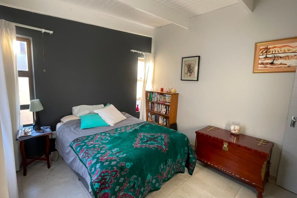 A bedroom featuring tiled flooring and an exposed beam ceiling, with a neutral color palette and a dark accent wall.