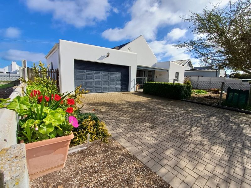 Front elevation of a modern house featuring a paved driveway, a secure garage, and a well-maintained exterior facade.