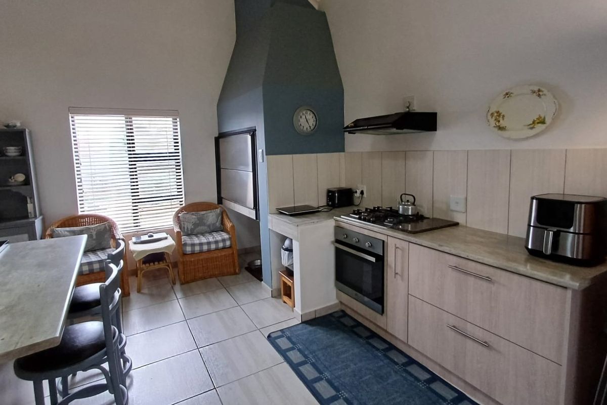 A functional kitchen featuring built-in cabinetry, gas hob, oven, extractor fan, and a unique built-in fireplace, finished with tiled flooring and backsplash.