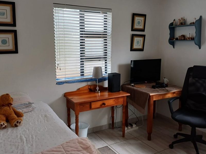 A functional bedroom featuring tiled flooring and dual windows fitted with venetian blinds, offering a neutral space ready for personalization.