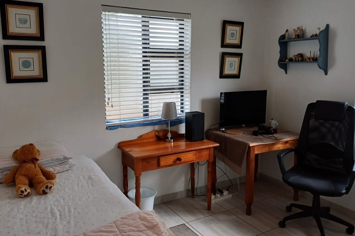 A functional bedroom featuring tiled flooring and dual windows fitted with venetian blinds, offering a neutral space ready for personalization.