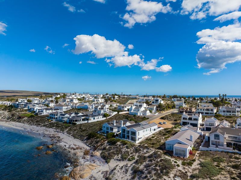 Aerial view of a coastal residential estate featuring multiple homes, paved streets, and direct access to the shoreline.