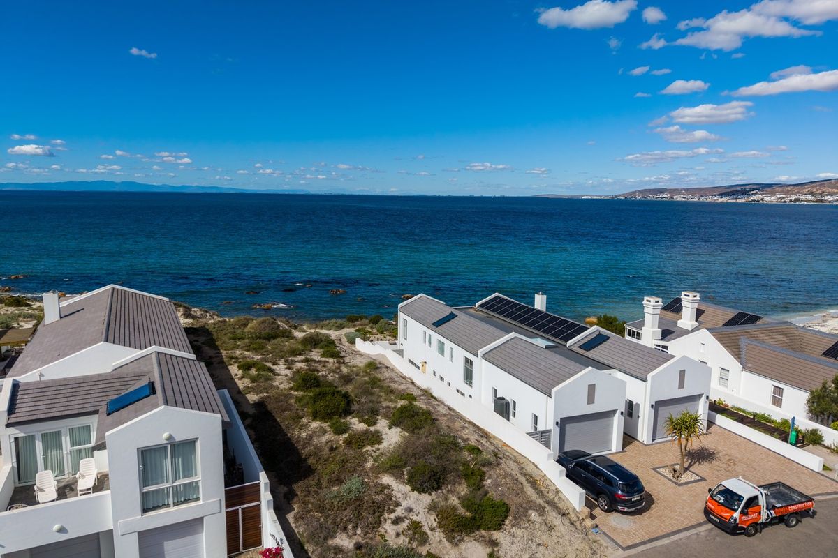 Aerial view of coastal residential properties featuring modern architecture, solar panels, and direct proximity to the ocean.