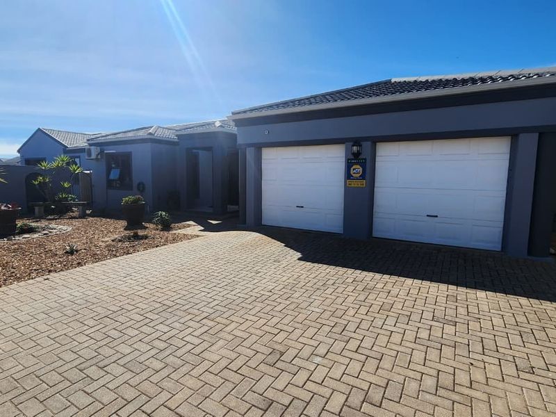 Front elevation of a modern house featuring a double garage, paved driveway, and low-maintenance landscaped garden area.