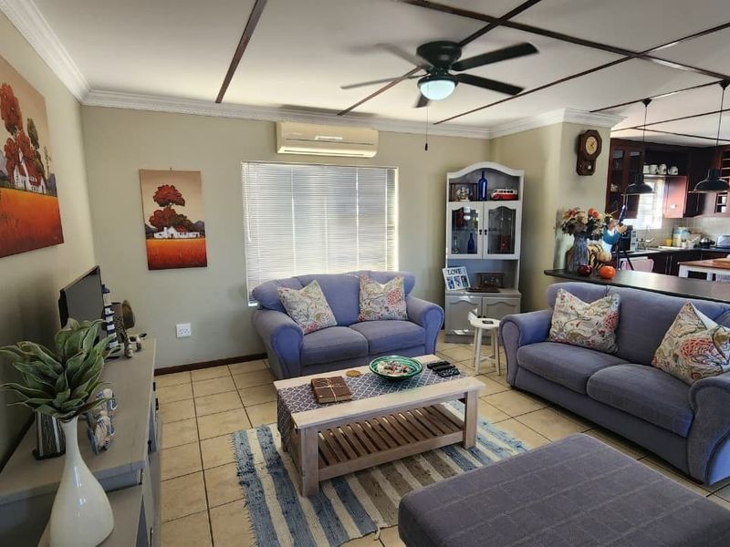 Open-plan living and kitchen area featuring tiled floors, a ceiling fan, split-system air conditioning, and dark wood kitchen cabinetry.