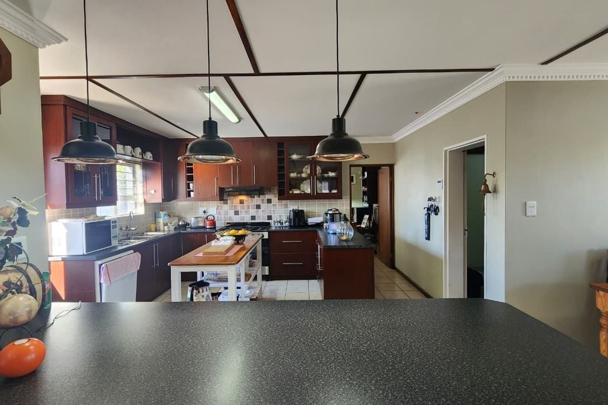 A functional kitchen featuring dark wood cabinetry, granite countertops, tiled backsplash, and modern pendant lighting, offering a practical layout for cooking and meal preparation.