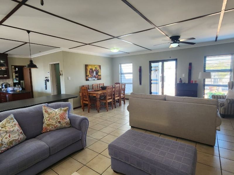 Spacious open-plan living and dining area featuring tiled floors, a ceiling fan, and an integrated kitchen with ample cabinetry.