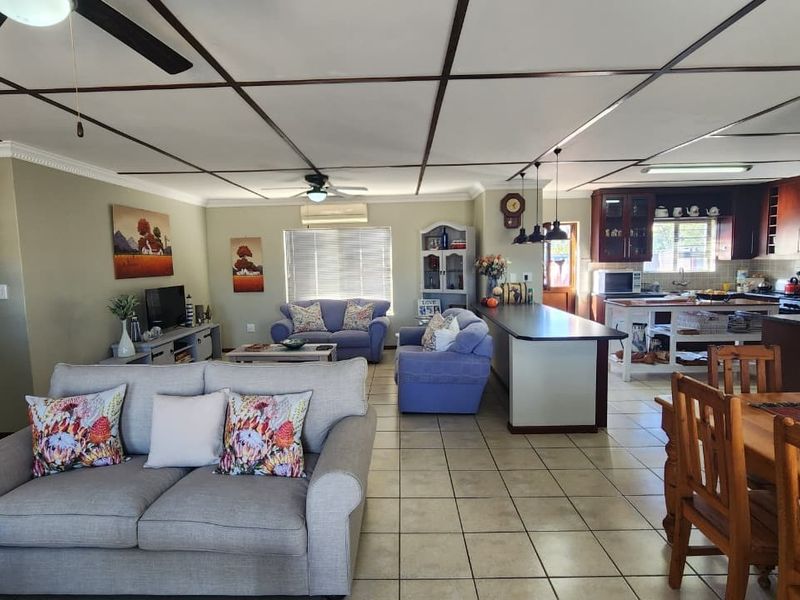Spacious open-plan living area featuring tiled floors, a central kitchen island with pendant lighting, and a functional kitchen layout with built-in cabinetry.