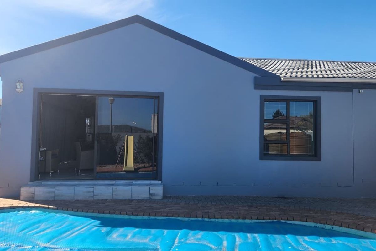 Rear exterior view of the house featuring a swimming pool, paved patio area, and sliding glass doors leading into the living space.