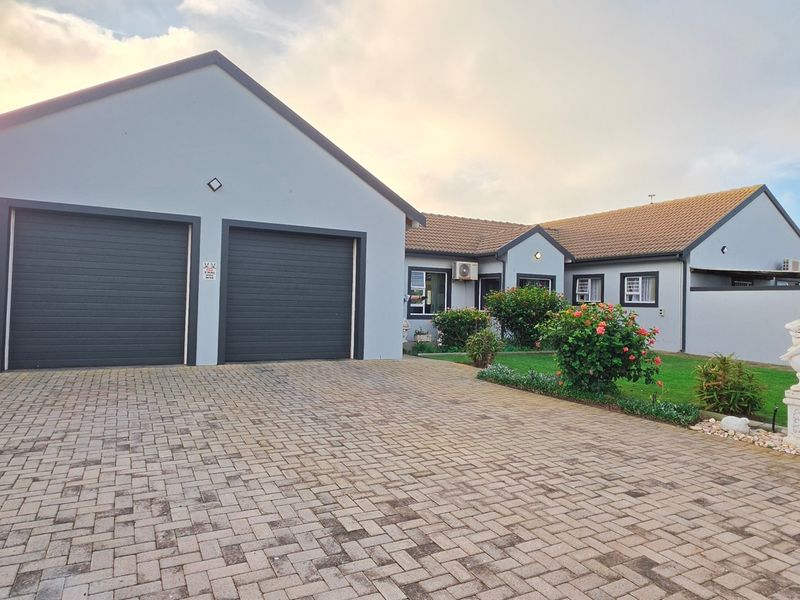Front view of a well-maintained house featuring a double garage, paved driveway, and landscaped garden area.