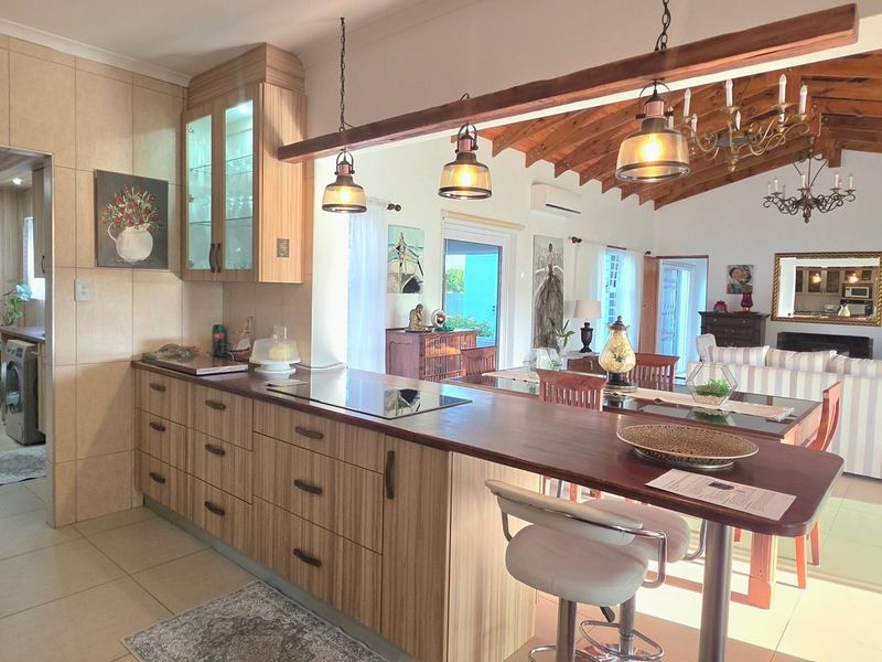 Spacious open-plan kitchen and living area featuring a breakfast bar, modern cabinetry, and exposed timber ceiling beams, creating a warm and inviting atmosphere.