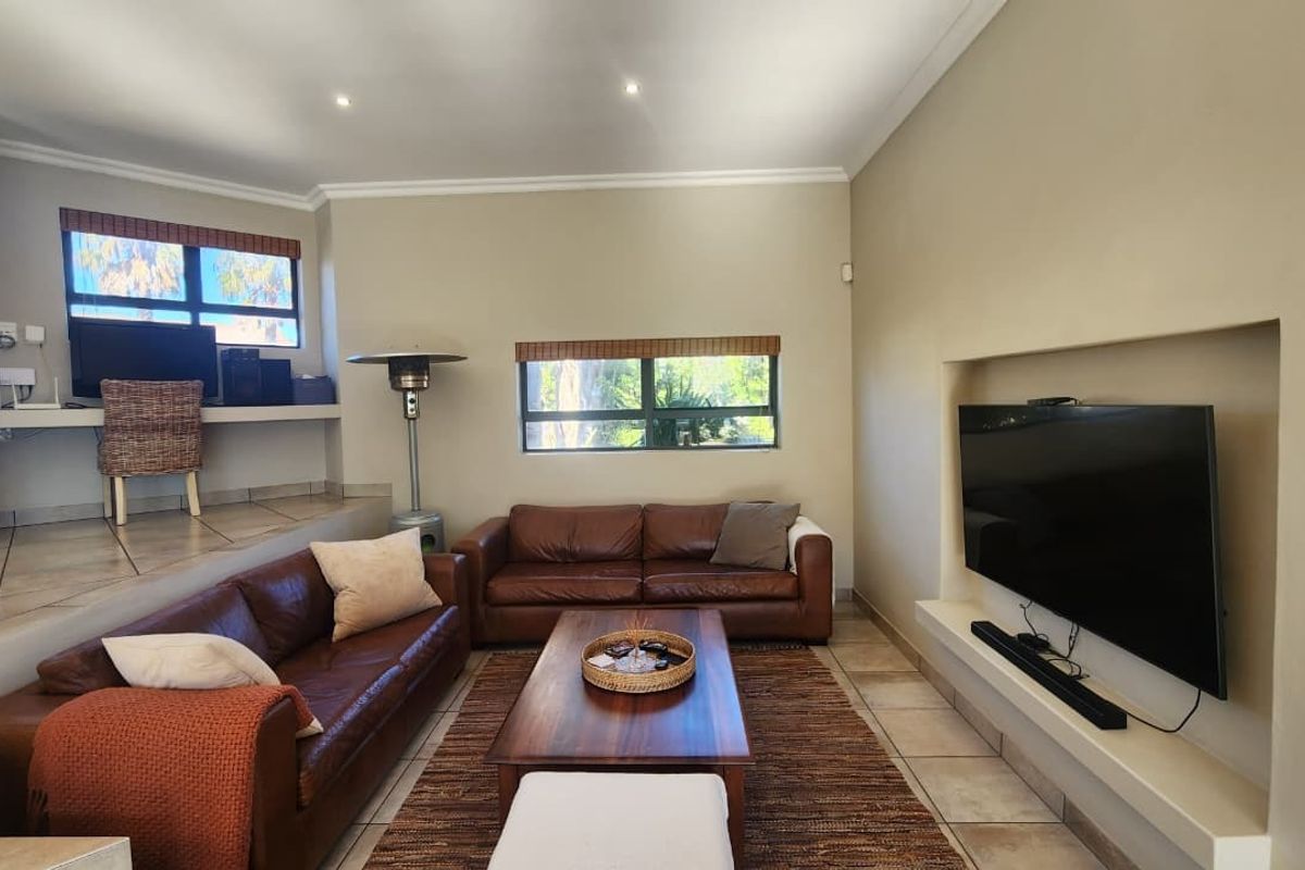 Spacious living room featuring a sunken seating area, a dedicated built-in desk nook, and a recessed wall niche for a television.