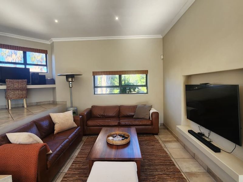 Spacious living room featuring a sunken seating area, a dedicated built-in desk nook, and a recessed wall niche for a television.