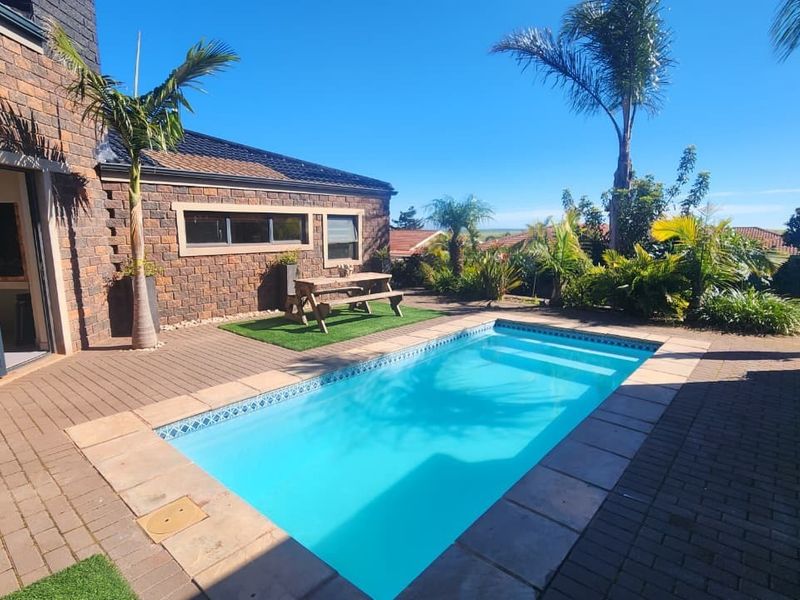 A well-maintained outdoor pool area featuring brick paving, a swimming pool, and direct access to the home through aluminium framed doors.