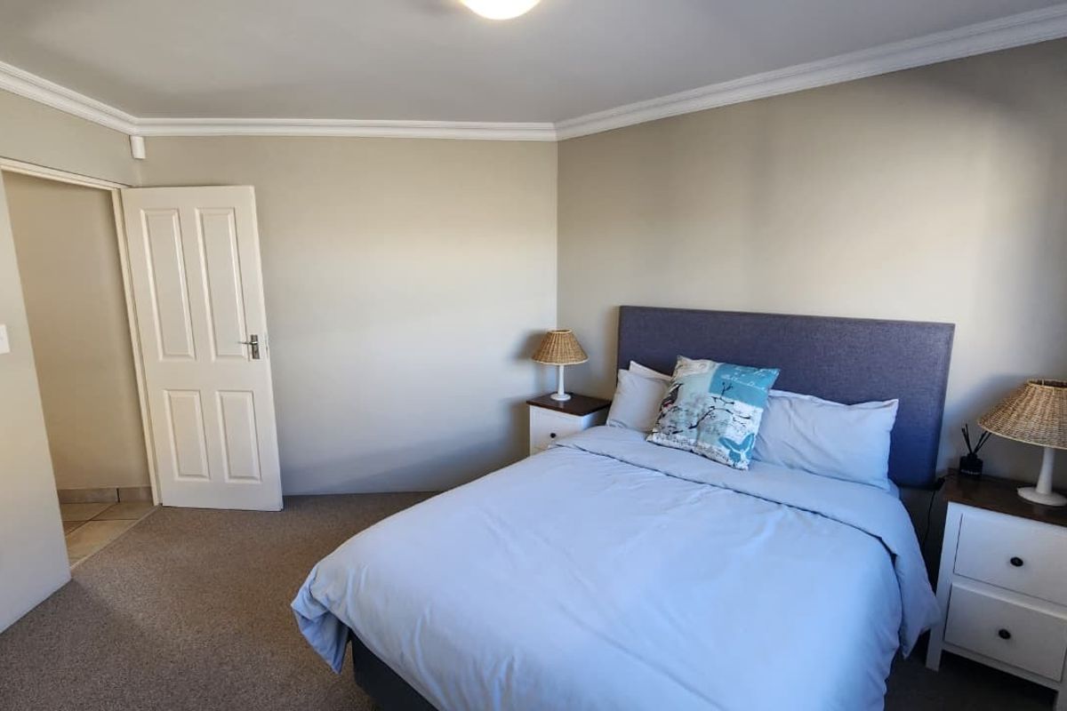 A well-maintained bedroom featuring neutral wall tones, carpeted flooring, and classic cove cornice detailing.