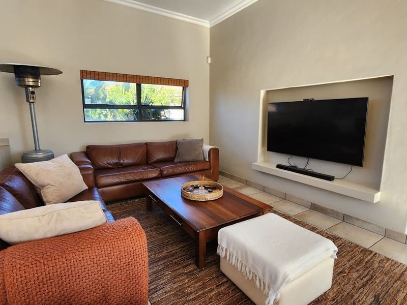 A comfortable living room featuring a built-in television niche, tiled flooring, and coved ceiling details.