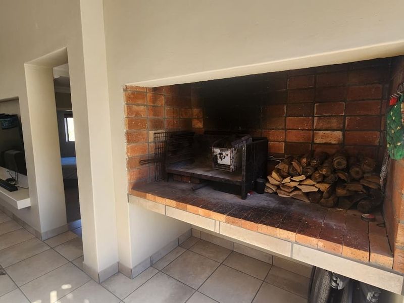 Living area featuring a built-in brick braai fireplace and tiled flooring, providing a functional space for indoor entertaining.