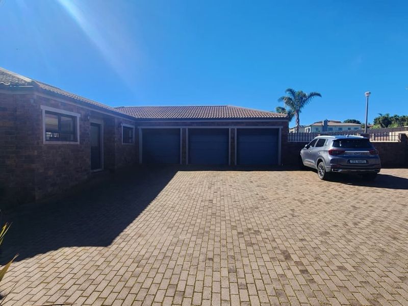 Spacious front exterior featuring a large brick-paved driveway and a triple garage with a facebrick facade and tiled roof.