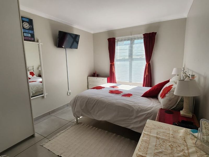 A functional bedroom featuring tiled flooring, a built-in wardrobe, and a window with blinds, offering a clean and practical living space.