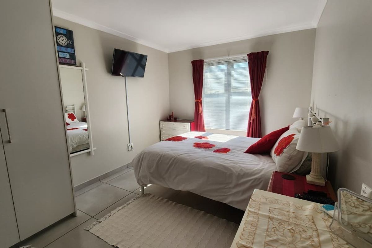 A functional bedroom featuring tiled flooring, a built-in wardrobe, and a window with blinds, offering a clean and practical living space.