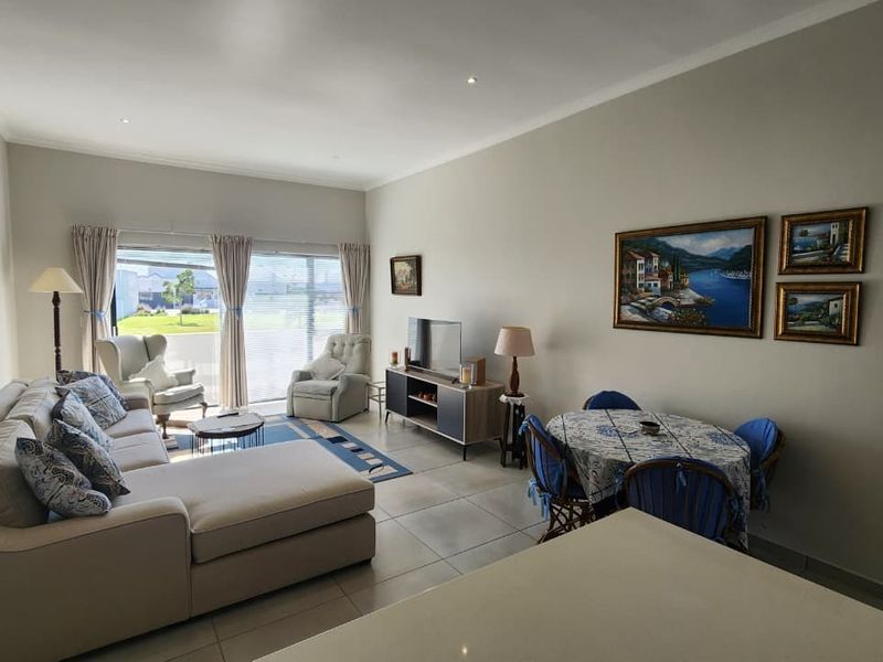 Spacious open-plan living and dining area featuring neutral tiled flooring, recessed lighting, and large sliding glass doors providing ample natural light.