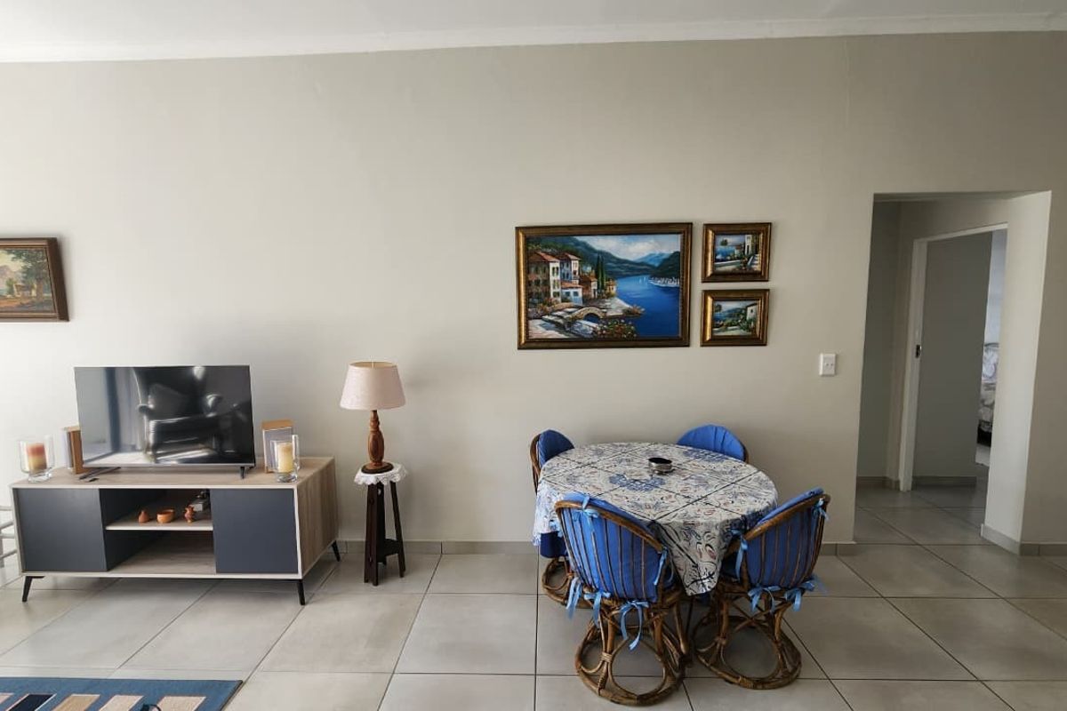 A living area featuring neutral wall tones and large format floor tiles, providing a clean and functional space for relaxation and dining.