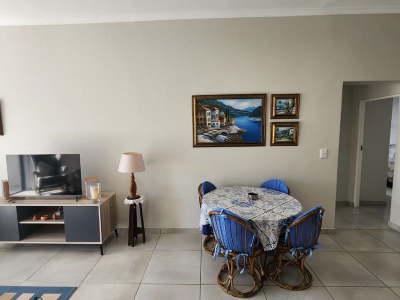A living area featuring neutral wall tones and large format floor tiles, providing a clean and functional space for relaxation and dining.