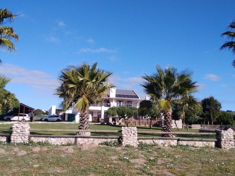 Front view of the small holding property featuring a landscaped garden, stone boundary wall, and solar panels installed on the roof.