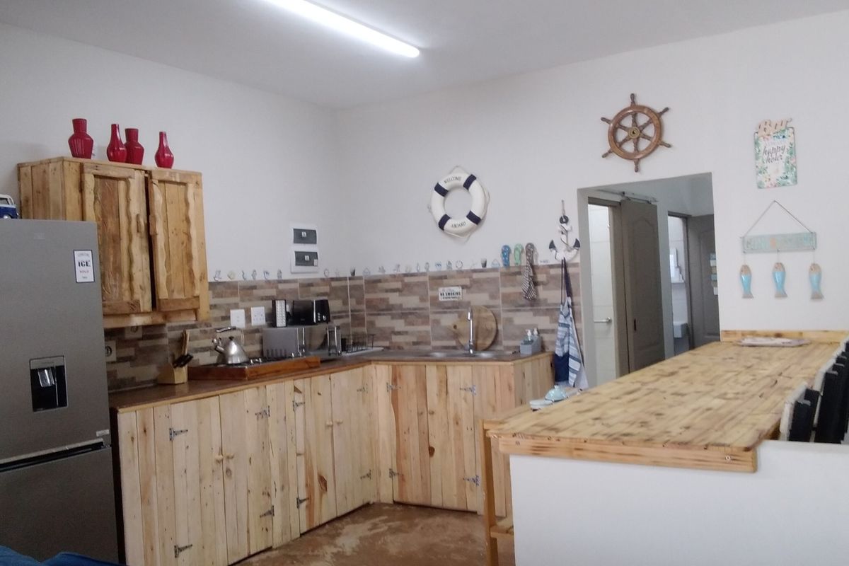 Kitchen featuring rustic wooden cabinetry, a matching breakfast bar, tiled backsplash, and stainless steel sink, offering a functional prep and dining space.