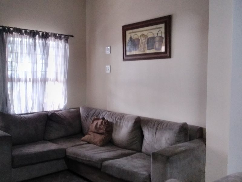 A living room area featuring neutral wall tones and a window with a curtain rod.