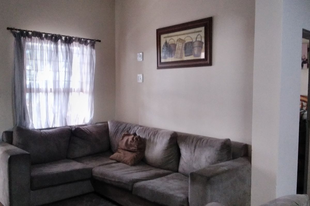A living room area featuring neutral wall tones and a window with a curtain rod.