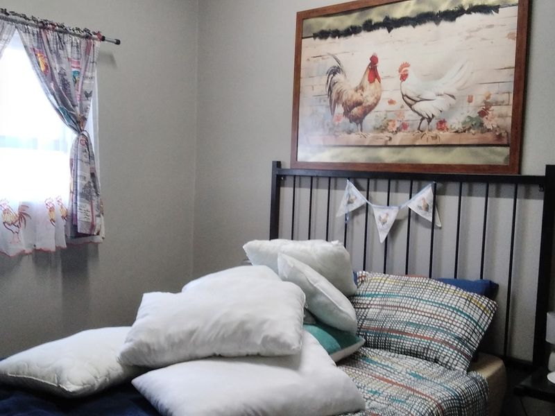 A bedroom featuring neutral wall tones and a window with decorative curtains.