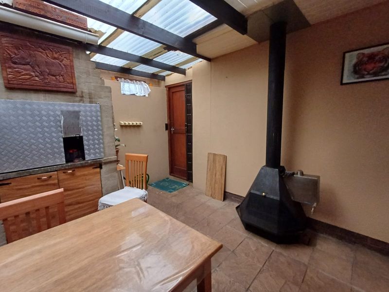 Covered patio area featuring a built-in braai, a freestanding fireplace, and tiled flooring, providing a functional space for outdoor entertaining.