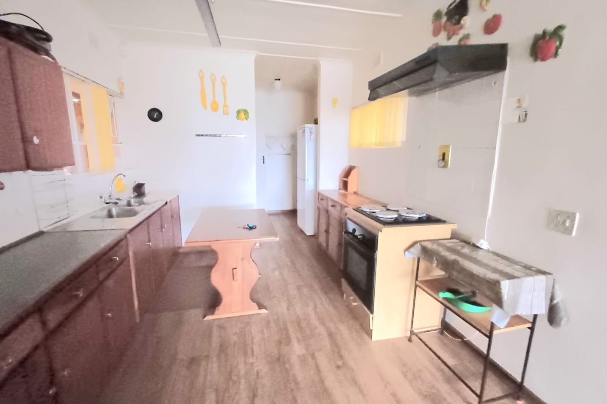 A functional kitchen featuring built-in cabinetry, a stainless steel sink, and a built-in oven with an extractor fan.