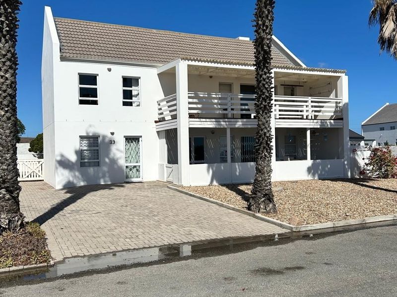A double-story residential property featuring a paved driveway, a covered balcony, and a low-maintenance gravel garden area.