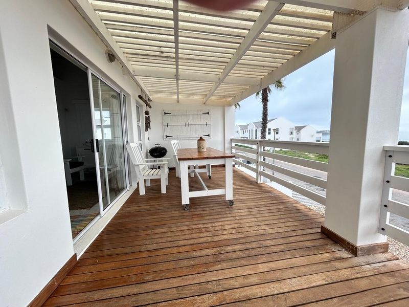 Covered balcony featuring timber decking and a slatted pergola roof, providing an outdoor entertainment space with direct access to the interior.