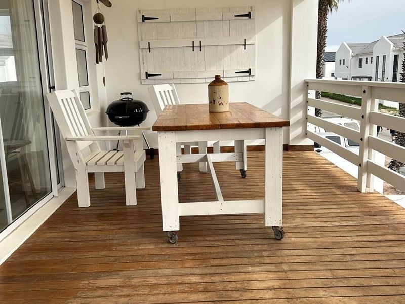 Covered outdoor patio featuring timber decking, a slatted pergola roof, and direct access to the interior via sliding glass doors.