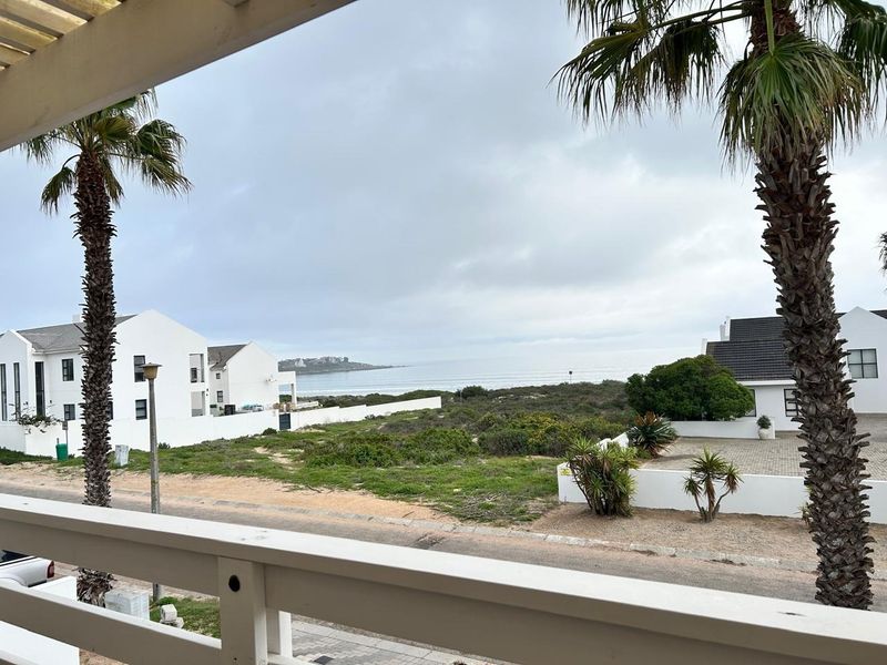 Elevated coastal view overlooking the surrounding neighborhood, natural landscape, and ocean horizon from a private balcony.