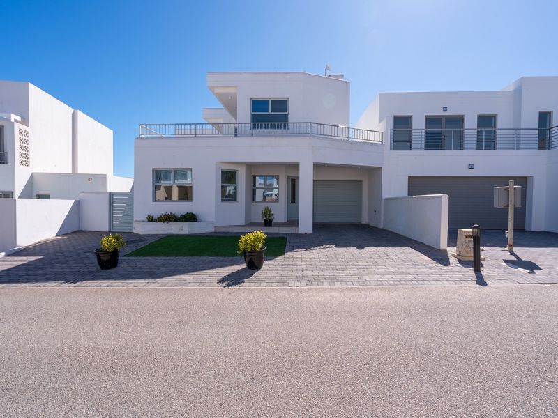 Modern two-story residential property featuring a paved driveway, integrated garage, and a balcony with metal railing.