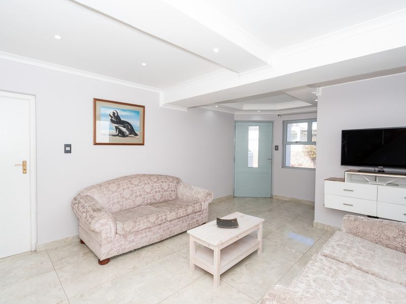 A bright living room featuring neutral tiled flooring, recessed ceiling lighting, and a coved ceiling design.