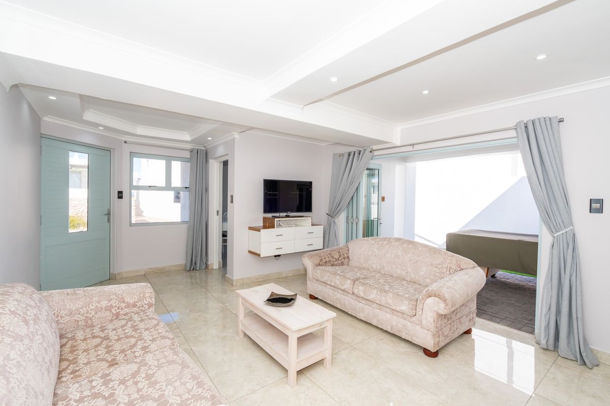 Bright and spacious living room featuring polished tiled flooring, recessed ceiling lighting, and direct access to an outdoor patio area through sliding glass doors.