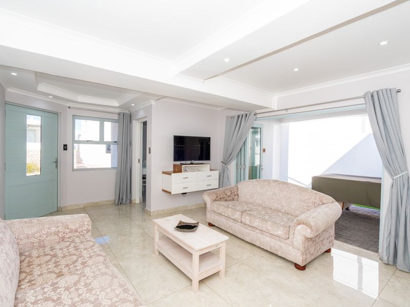Bright and spacious living room featuring polished tiled flooring, recessed ceiling lighting, and direct access to an outdoor patio area through sliding glass doors.