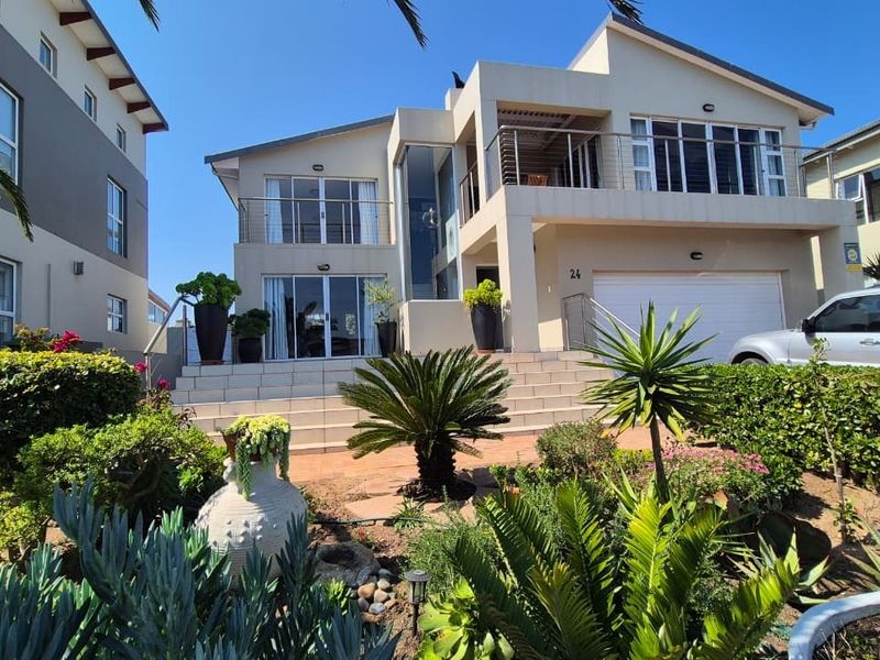 Modern double-story residential home featuring a tiled entrance staircase, balcony, and integrated double garage, set within a well-maintained landscaped garden.
