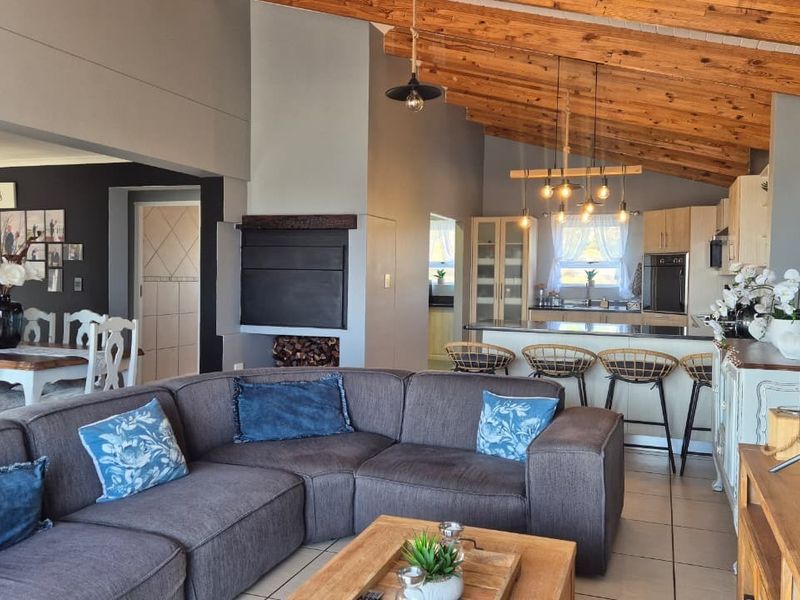 Spacious open-plan living area featuring exposed timber ceiling beams, a built-in fireplace, and a modern kitchen with a central island and integrated appliances.