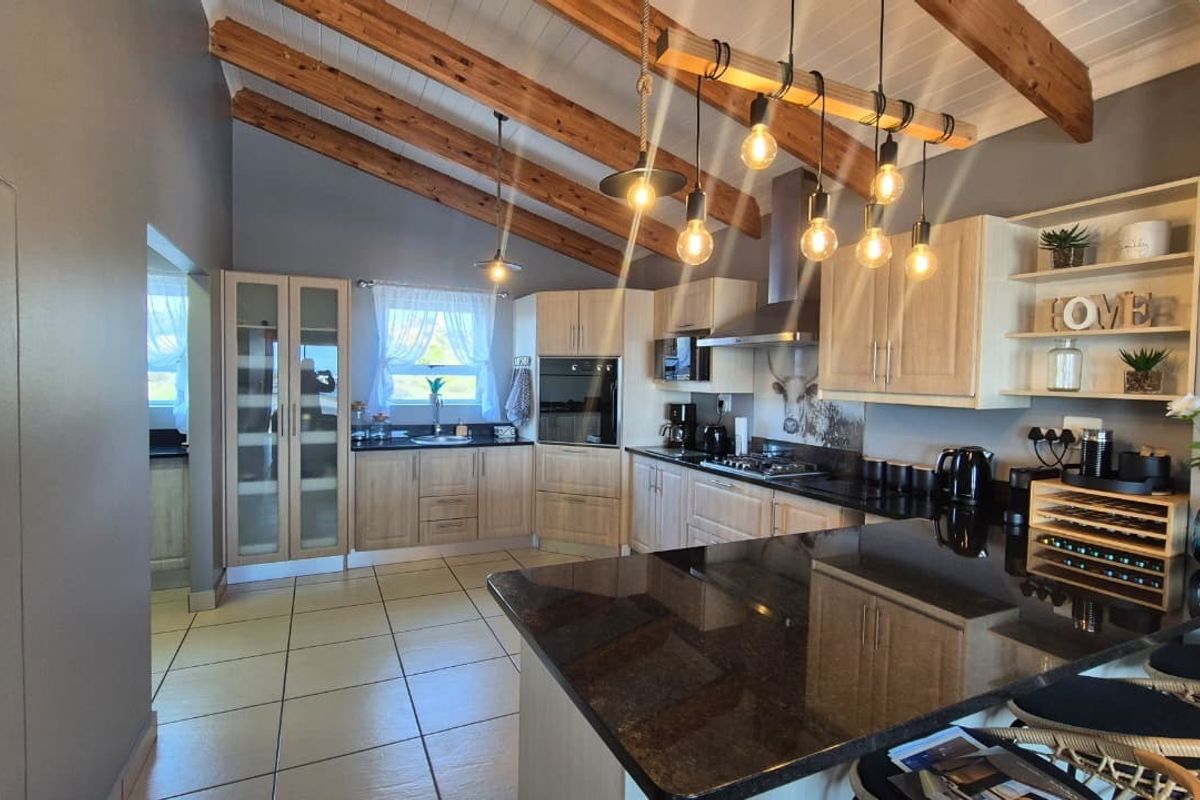 Modern kitchen featuring granite countertops, built-in cabinetry, stainless steel appliances, and striking exposed timber ceiling beams, creating a warm and functional culinary space.