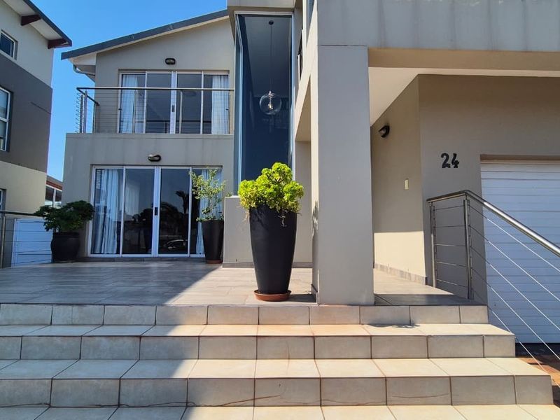 Modern front entrance featuring a tiled staircase, stainless steel balustrades, and large sliding glass doors leading into the home.