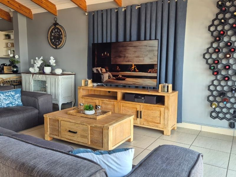 Open plan living area featuring exposed timber ceiling beams, tiled flooring, and a seamless transition to the kitchen space.