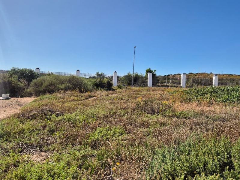 A large, undeveloped garden area featuring perimeter fencing and concrete pillars, offering significant potential for landscaping and outdoor development.